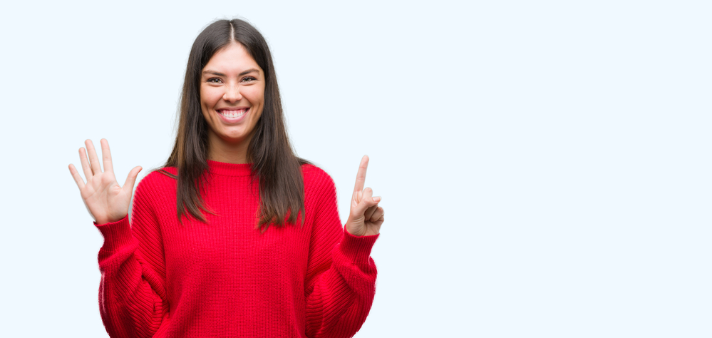 Young beautiful hispanic wearing red sweater showing and pointing up with fingers number six while smiling confident and happy.