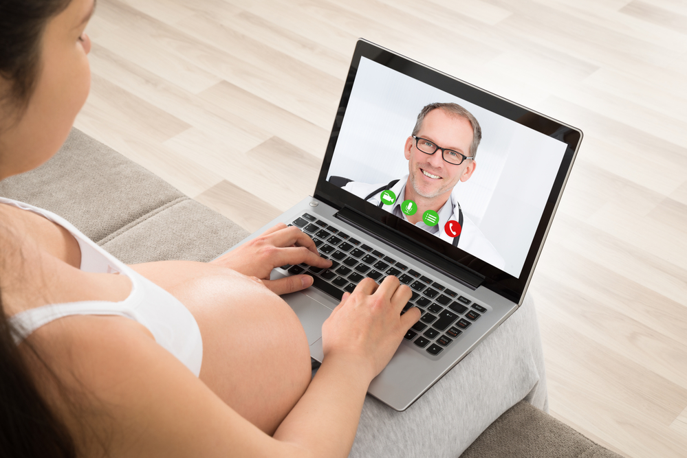 Pregnant Woman Videoconferencing With Doctor On Laptop
