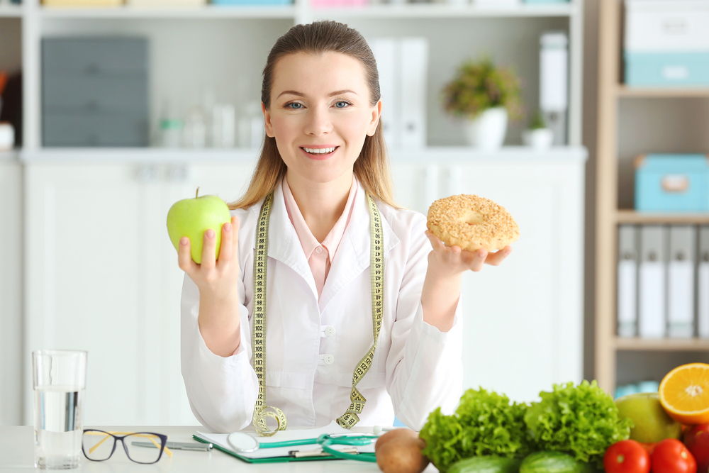 Young female nutritionist with food in her office
