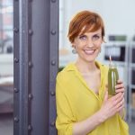 Happy woman with green health drink at work