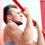 young man exercising on horizontal bar outdoors